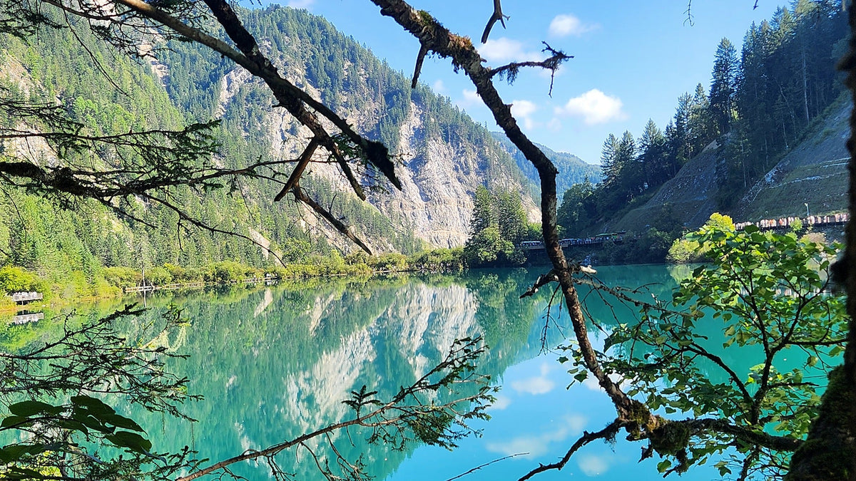 emerald lake with mirror reflections of forested slopes in Jiuzhaigou